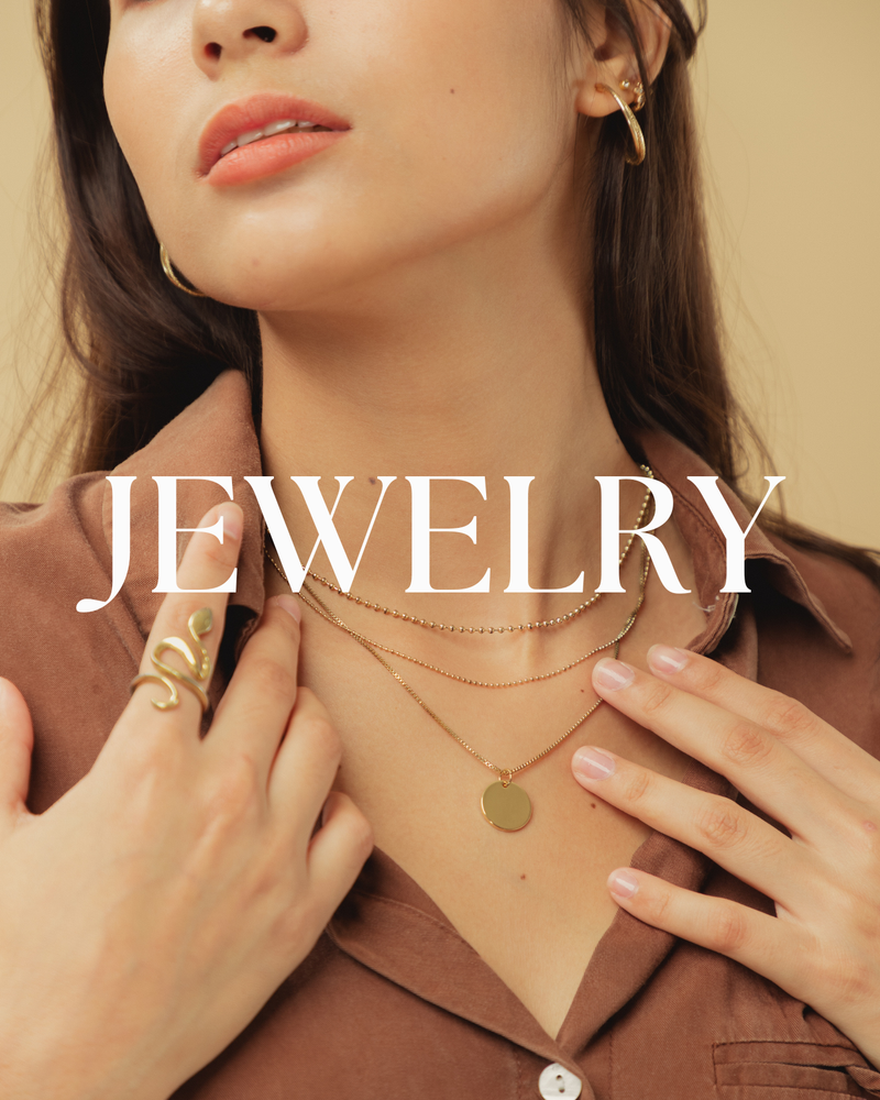 Woman wearing gold jewelry including earrings, necklace, and ring on a beige background with 'JEWELRY' text overlay.